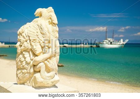 Pefkohori, Greece - May 17, 2016: Sculpture Statue On Sandy Beach And Ship Boat On Blue Paradise Wat