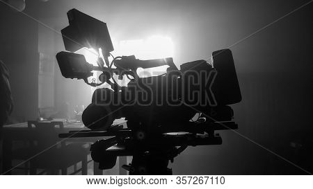 Movie Camera On The Slider In The Backlight From The Window, The Rays Of The Sun In A Smoky Room