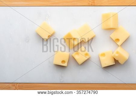 Portions (cubes, Dice) Of Emmental Swiss Cheese . Texture Of Holes And Alveoli. On White Marble Tabl