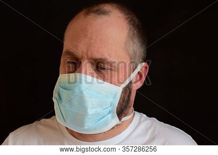 Man In A Medical Mask On A Black Background. Portrait, Close-up. Bokeh. Selective Focus.