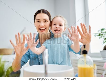 A cute little girl and her mother are washing their hands. Protection against infections and viruses.                                