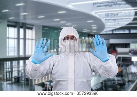 Man Epidemiologist In Coverall Disposable Anti-epidemic Antibacterial Isolation Suit Shows A Prohibi