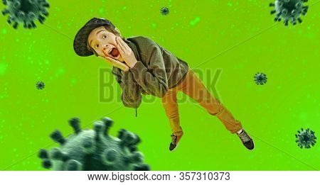 Cool emotional teen boy screams in surprise and jand fear on a green background with bacilli. Full length, copy of space.