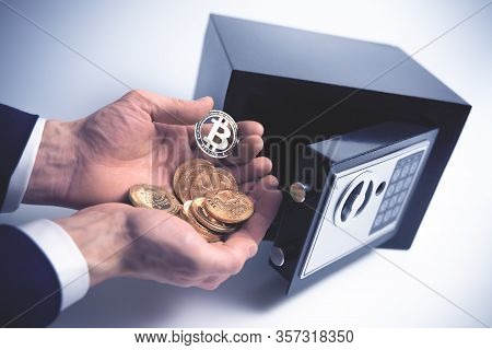 Safe Deposit. Symbol Of Cryptocurrency Safety. The Man Puts A Physical Bitcoin In Small Residential 