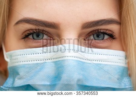 Beautiful Women In A Medical Mask. Close-up Of A Young Woman With A Surgical Mask On Her Face Agains
