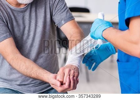 Young male doctor and old patient in first aid concept