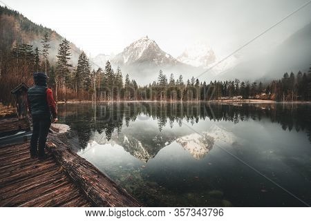 Man Standing At A Mountain Lake Enjoying The Sunrise In The Austrian Alps