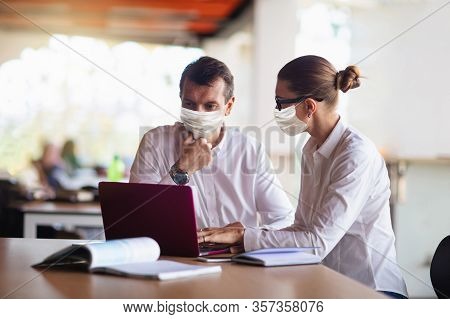 Businessman And Businesswoman In Face Masks At Work. Corporate Meeting During Coronavirus Outbreak.