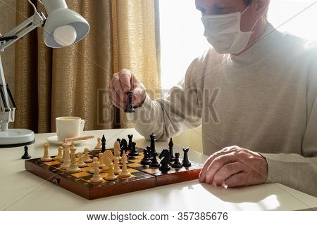 A Man In A Medical Mask In Quarantine Plays Chess. Quarantine, Covid-19, Self-isolation Concept. Hor