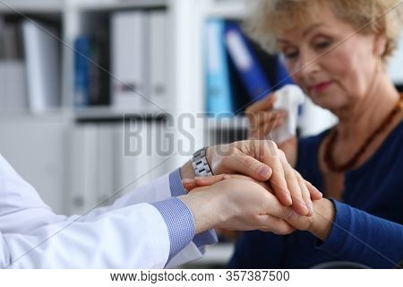 Focus On Male Hands Of Doctor Holding Arms Of Sick Elderly Woman. Therapist Supporting And Calming I