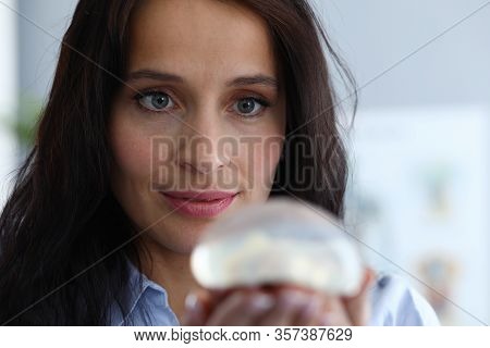 Close-up Of Focused Woman Looking Attentively At Silicone Implants With Interest. Smiling Lady Think