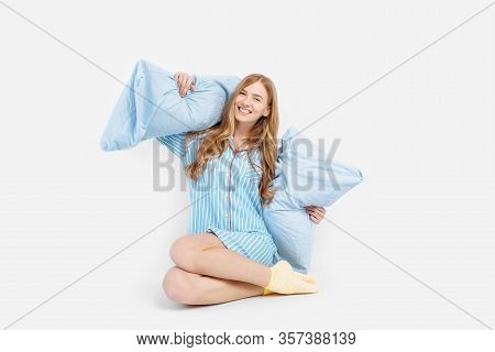 Beautiful Girl In Pajamas, Sitting On The Bed With Pillows In Her Hands, On A White Background