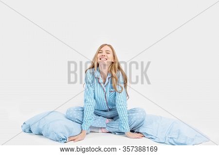 Beautiful Girl In Pajamas, Sitting On The Bed With Pillows In Her Hands, On A White Background