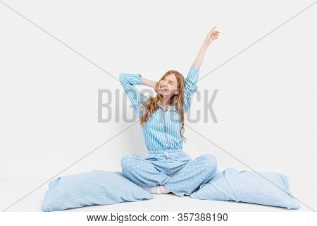 Beautiful Girl In Pajamas, Sitting On The Bed With Pillows In Her Hands, On A White Background