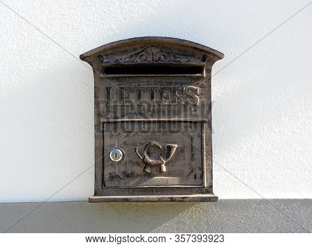 A Retro Looking Gray Mailbox, Or Letterbox, Affixed To The Exterior White   
 Wall