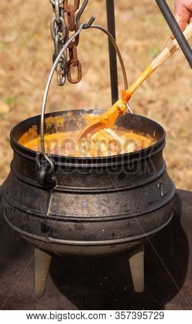 Stew cooking in a potjie cast iron pot over open fire outdoors