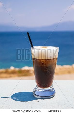Glass Of Yummy Iced Coffee Or Greek Freddo Cappuccino On The Seascape Background On A Summer Sunny D