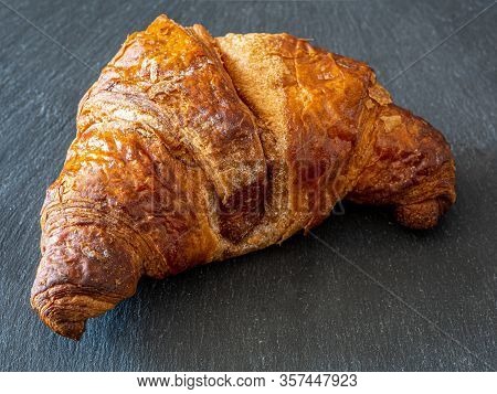 Traditional Croissant Placed On A Dark Plate, A Typical Dessert Similar To The Italian Cornetto