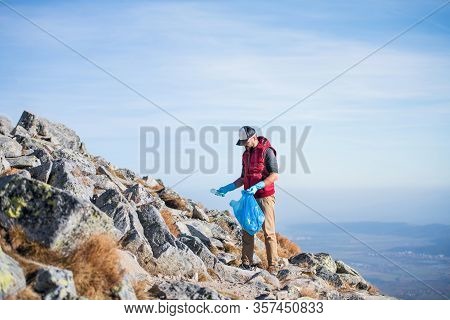 Man Hiker Picking Up Litter In Nature In Mountains, Plogging Concept.