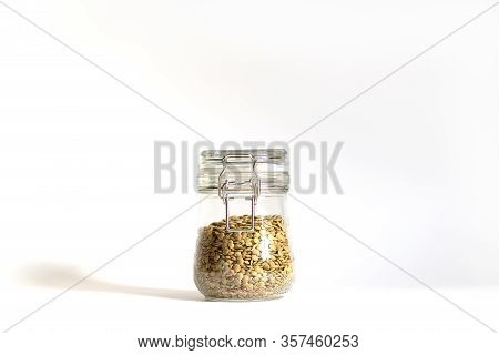 Green Lentils Tightly Closed In A Glass Bowl. One Jar Stands On A White Background In Daylight With 