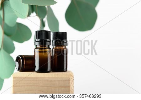 Cosmetic Glass Bottles With Green Eucalyptus Leaves. Unbranded Amber Containers On Wooden Stand For 