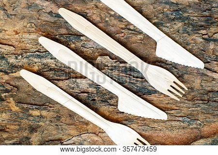 Wooden Cutlery On A Piece Of Bark From A Tree. Eco-friendly Knives And Forks On A Wooden Background.