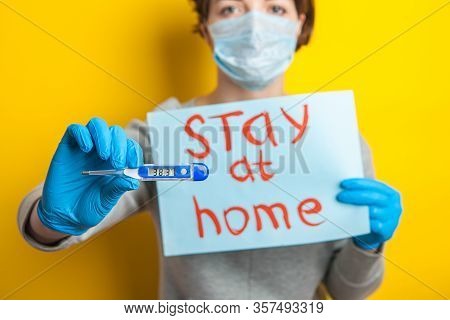Woman In A Medical Mask With A Temperature. Holding A Thermometer In His Hands. Mild Condition Of A 