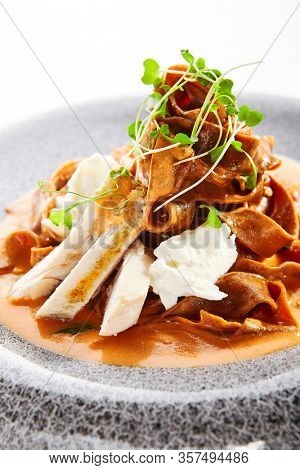 Spaghetti with baked tomato and chicken. Served traditional Italian cuisine. Borodinsky flour pasta with tomato sauce in plate. Italy culinary. Restaurant food portion, main course close up