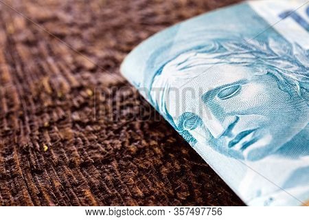 Detail Of A Banknote Of One Hundred Reais From Brazil, Rustic Wooden Background. Concept Of Personal