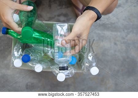 Hand  Holding Clear And Green Recyclable Plastic Bottle Putting In Paper Garbage Bin For Recycling.
