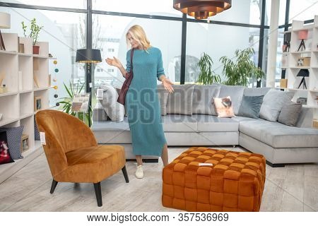 Blond-haired Woman Standing In Indecision In A Furniture Store.