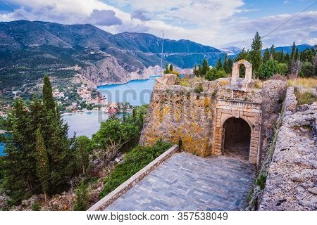Old Fort Gate On Top Of Frourio Peninsular And Assos Village With Beautiful Sea Bay And Cypress Tree