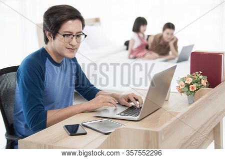 Asian Businessman And Father Working At Home With Notebook Computer, Tablet, And Smartphone While Hi