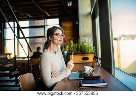 Female College Student Thinking During Online Learning On Laptop Computer While Sitting In Contempor