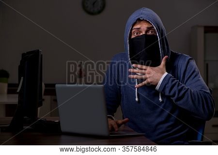 Male hacker hacking security firewall late in office