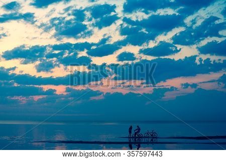A Couple On Bicycles Arrived On A Summer Beach In Jurmala To Spend A Day At Sunset. Jurmala, Latvia