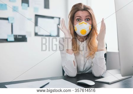 Young Blond Woman Manager In Medical Protection Mask And Gloves Looks Panicky While Working In Offic