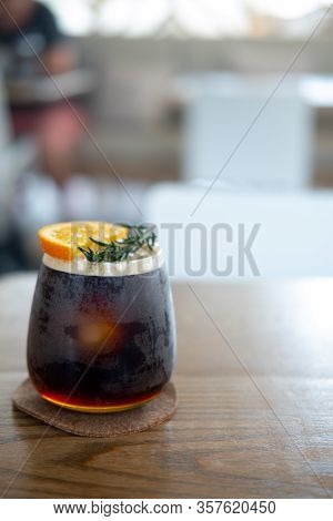 Glass Of Espresso Shot Mixed With Orange Juice On Wood Table. Refreshing Summer Drink Concept