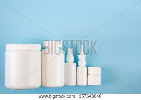 Various White Plastic Medical Containers Set On Light Blue Background. Virus Or Flu Or Cold Treatmen