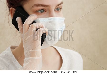 Young Woman In Medical Mask And Gloves Speaks On Smartphone. New Outbreak Of Coronavirus Covid-19