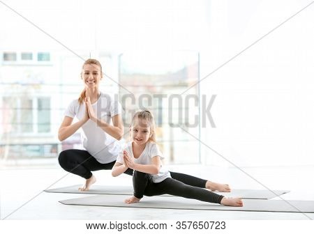 Mother And Daughter In Matching Sportswear Doing Yoga Together At Home