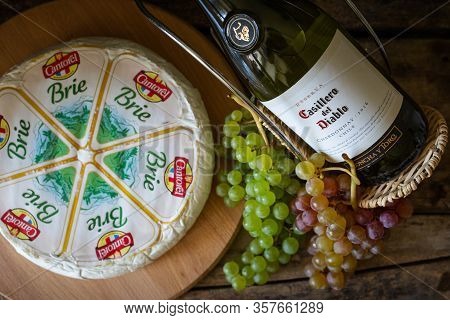 Cheese Brie With Bottle Of Chardonnay Of Casillero Del Diablo With Bunch Of Grapes On The Table