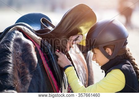 Young Girl Adjusting Her Sadle Before Horse Riding