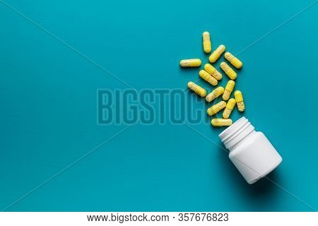 Vitamin capsules. Vitamin C pills and pill bottle on blue background. Top view.