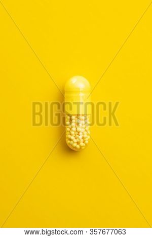 Vitamin capsule. Vitamin C pill on yellow background. Top view.