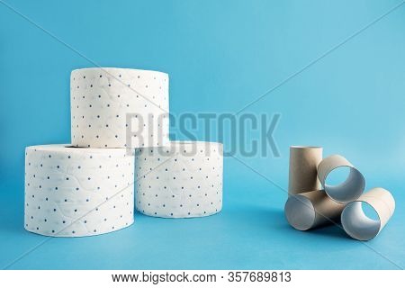 Several Rolls Of White Toilet Paper In A Blue Speck And Empty Rollers, Bushes Next To It. Blue Backg