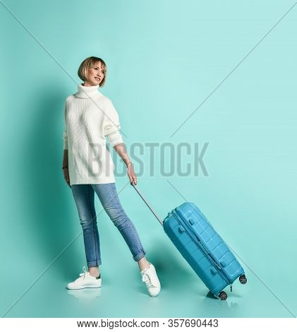 Attractive Blonde Girl In White Sweater, Jeans And Sneaker Smiling Posing With Suitcase Luggage Stan