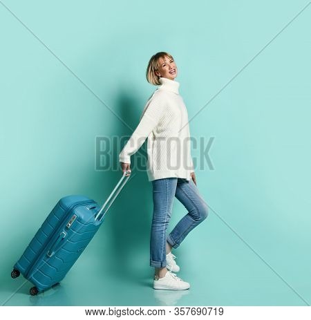Attractive Blonde Girl In White Sweater, Jeans And Sneaker Smiling Posing With Suitcase Luggage Stan