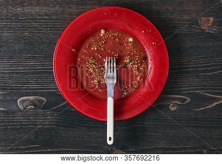 Salad Leftovers After Meal. Oil, Tomato Seeds, Chopped Parsley On A Single Red Plate With White Fork