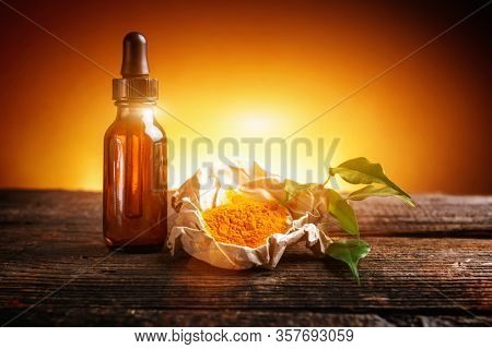 Tumeric powder spice on wooden board with essential oil as healthy supplement of diet